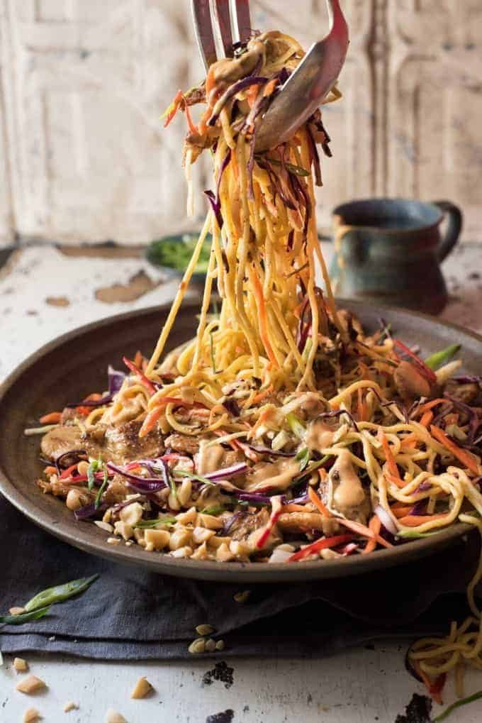 Satay Chicken Noodle Salad being tossed with dressing.