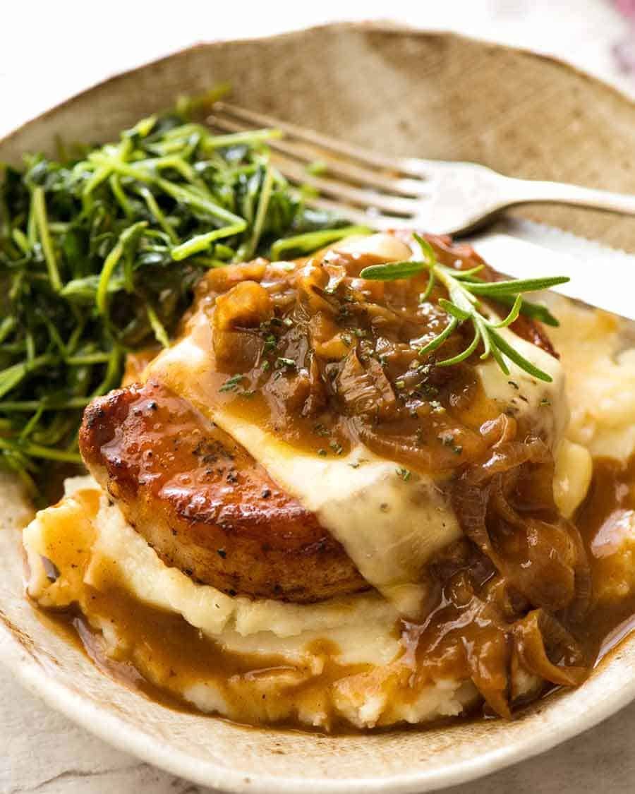 French Onion Smothered Pork Chops on mashed potato with a side of sautéed snow pea sprouts